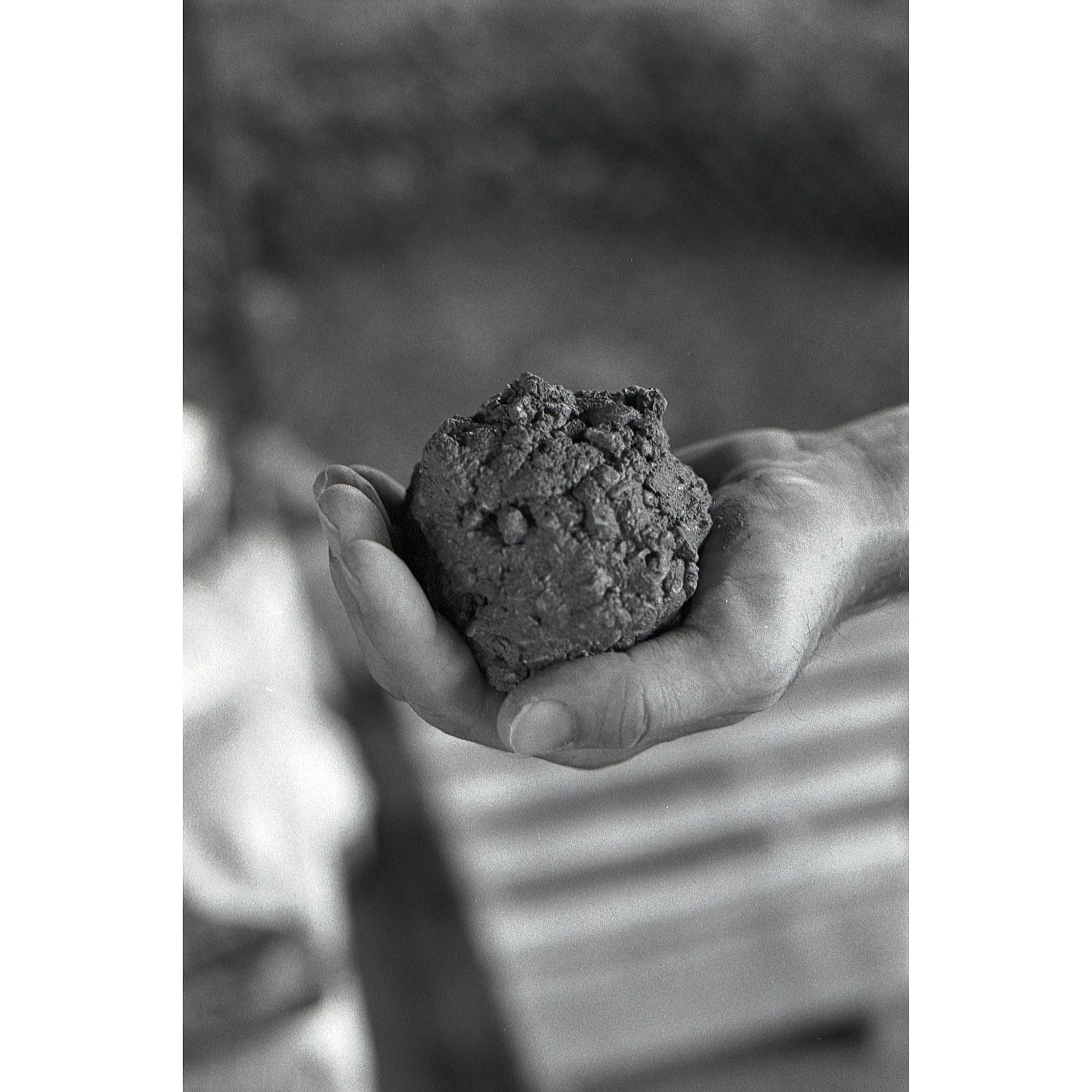 A black and white picture of a hand holding a ball of concrete.